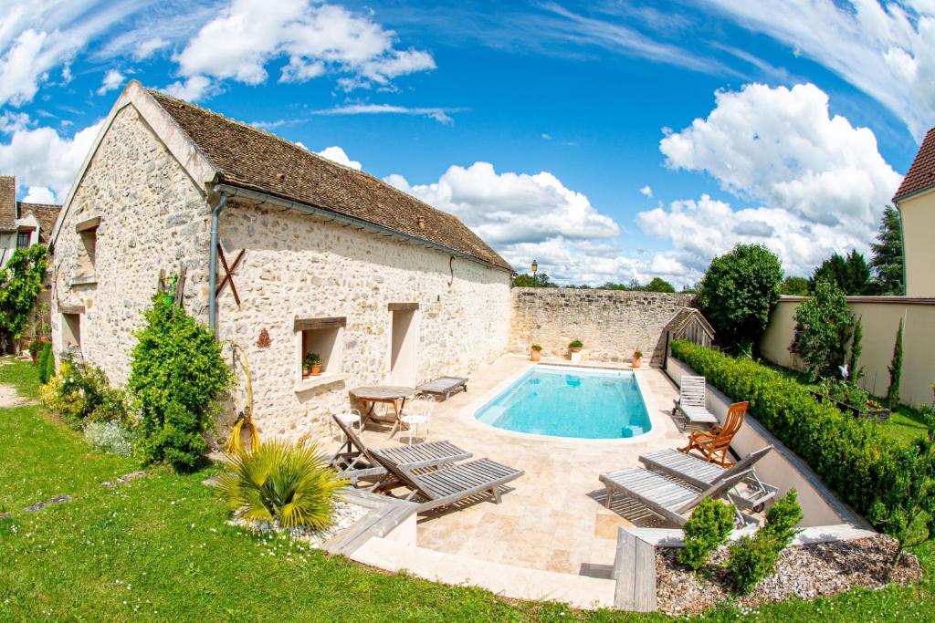 Courdimanche-sur-EssonnesCasa la Rosa & Spa的一座古老的石头建筑,在院子里设有游泳池