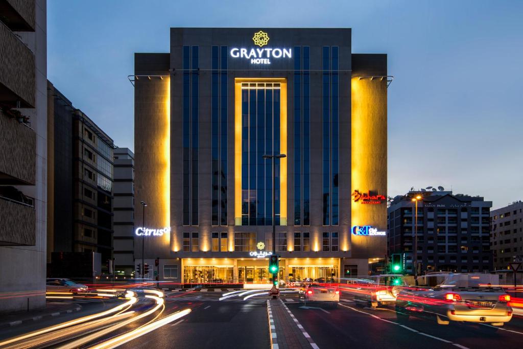 迪拜Grayton Hotel by Blazon Hotels的夜间在城市街道上驾驶汽车的建筑物