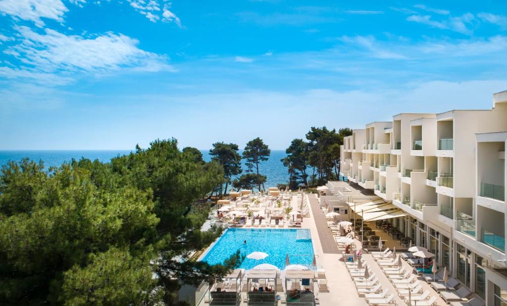拉布Valamar Carolina Hotel & Villas的享有带游泳池和椅子的度假村的空中景致
