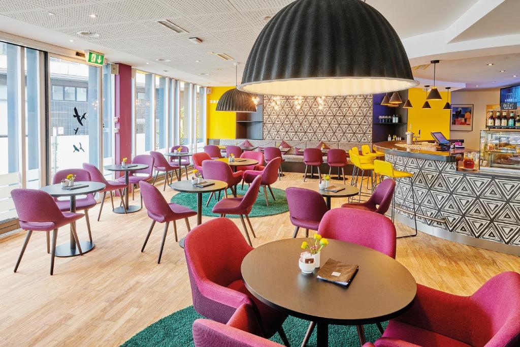 伯尔尼索列尔阿多尔酒店的一间设有紫色桌椅的餐厅和一间酒吧