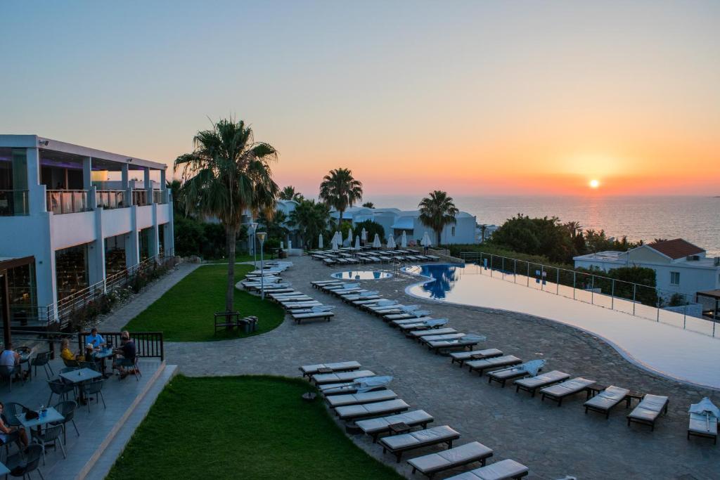 帕福斯Theo Sunset Bay Hotel的享有带躺椅的度假胜地和大海的景致。