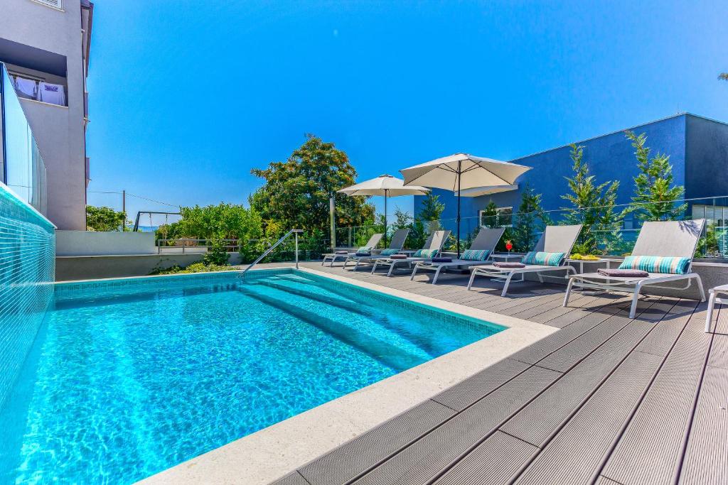 斯普利特Bel Residence的游泳池位于带椅子和遮阳伞的甲板上
