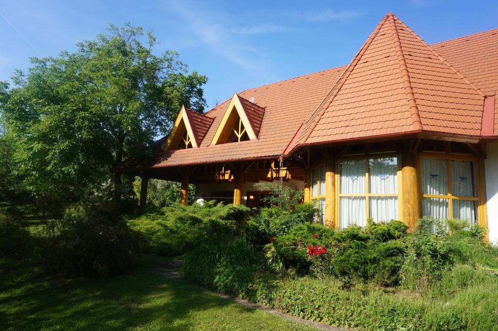 MonoszlóKiskúti Vendégház的一座红色屋顶的房子和一个院子
