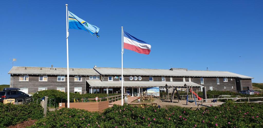 韦斯特兰Jugendherberge Westerland的两面旗帜在建筑物前飞
