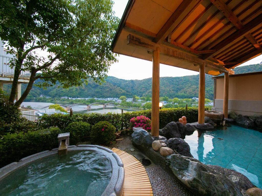 岩国市岩国市扣库赛䕋光酒店的一座花园内的热水浴池,位于一座建筑旁边