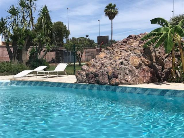 圣玛丽亚港Casa independiente con piscina y pista deportiva privadas的一个带两把椅子和岩石墙的游泳池