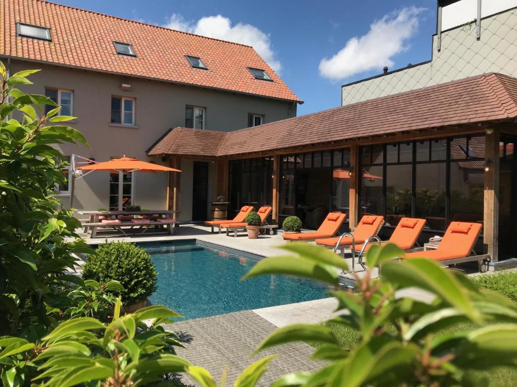德哈恩B&B d'Oude Brouwerij的一座带游泳池和橙色椅子的房子