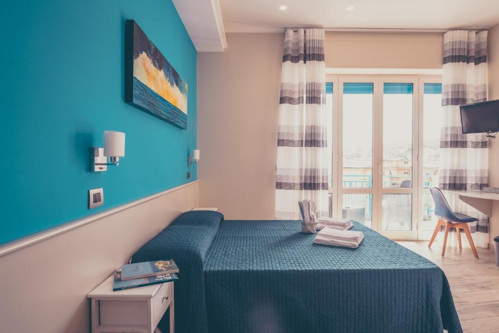 加埃塔Oltre il Mare Guest House的一间卧室配有一张蓝色墙壁的床和一扇窗户