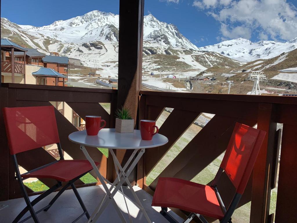 葱仁谷Val Thorens Temple of the Sun - ski in, ski out的雪覆盖的山景阳台上配有一张桌子和两把椅子