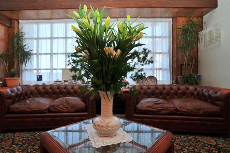 SorisoHotel Ristorante Al Sorriso的客厅配有沙发和花瓶(桌子上)
