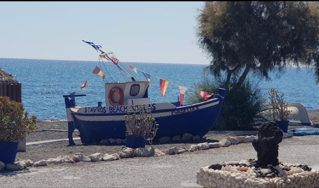 佩里沃罗Stavros Beach Villas的一艘蓝色的船坐在海滩上靠近水面