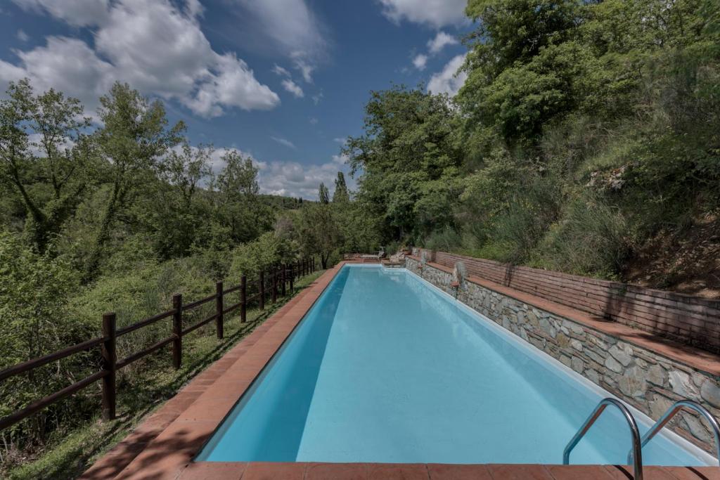 基安蒂盖奥勒Ultimo Mulino Wellness Country Hotel的一个带栅栏和树木的蓝色游泳池