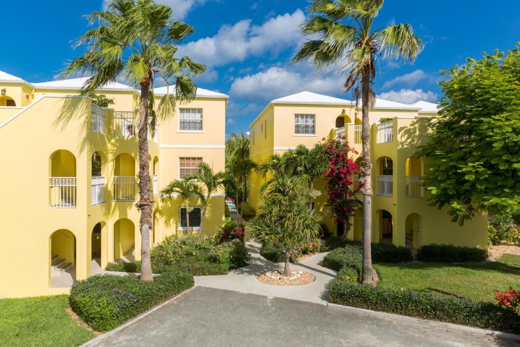 格雷斯湾格雷斯湾公寓式酒店的棕榈树和车道的黄色建筑