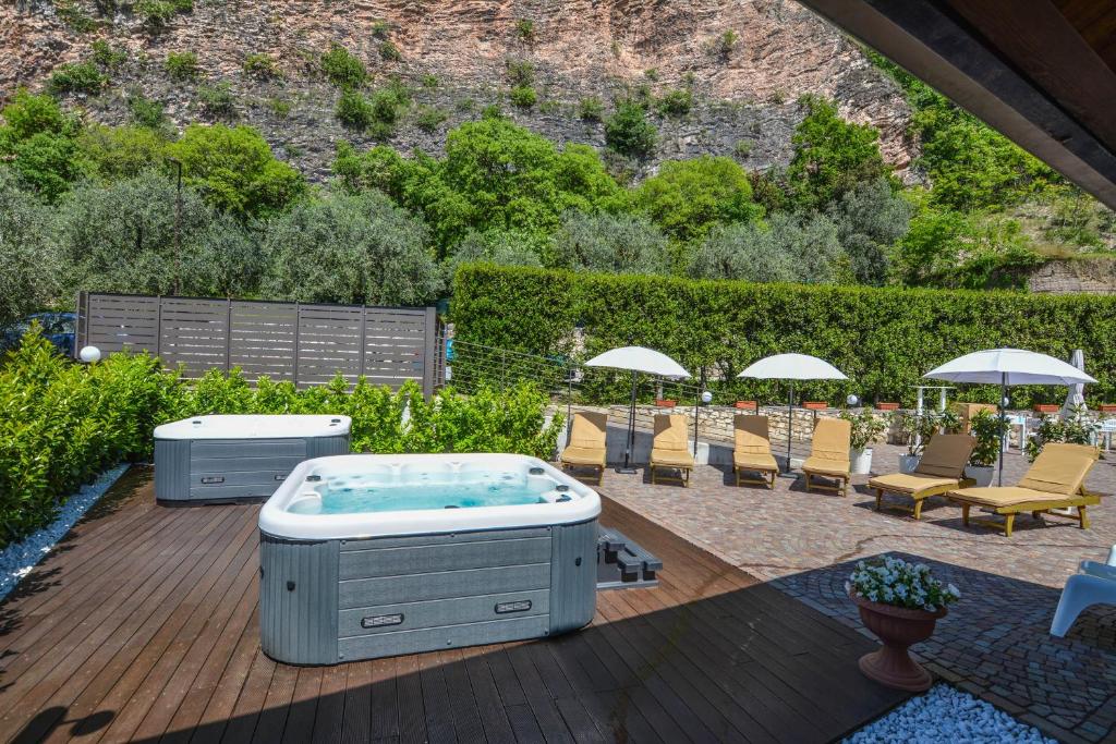 托尔博莱Villa degli Olivi Relais的甲板上的热水浴池配有椅子和遮阳伞