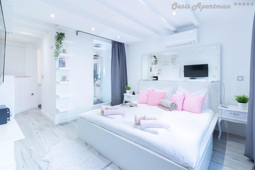 奥帕提亚Oasis Apartments Opatija的白色卧室配有大白色床和粉红色枕头
