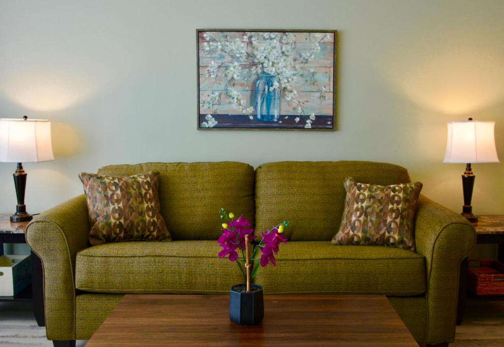 默特尔比奇One Bedroom Ocean View Condo的客厅里绿沙发,花瓶里放着鲜花