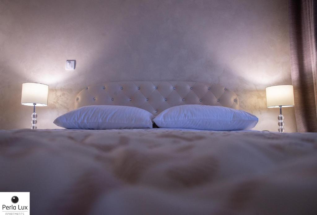 阿然德洛维克Perla Lux Apartments的一间卧室配有一张带枕头的床和两盏灯。