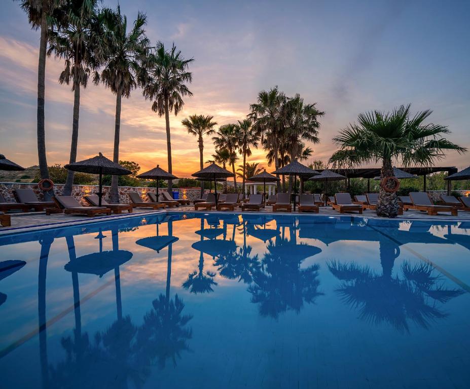 卡尔扎迈纳Argiri Resort Hotel & Apartments的一个带椅子和遮阳伞的游泳池以及棕榈树