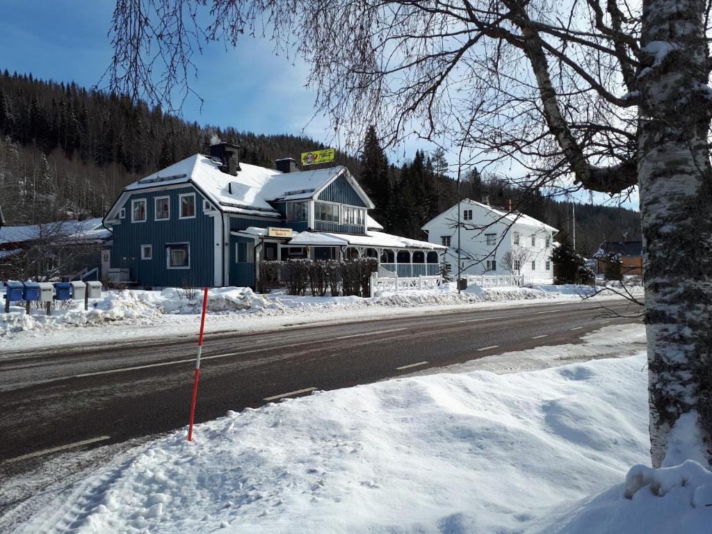希塞里贝克Wärdshuset Klarälvdalen的雪中道路边的蓝色房子