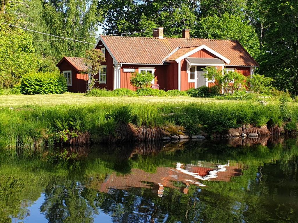 MölntorpWESTERQVARN的一条树木繁茂的河旁的红房子