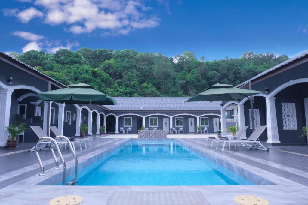 珍南海滩Cenang Rooms With Pool by Virgo Star Resort的一座带椅子和遮阳伞的游泳池位于一座建筑旁边