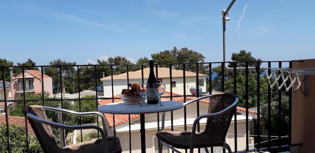 斯卡拉亚历山大公寓酒店的阳台上配有一张桌子和两把椅子,并提供一瓶葡萄酒