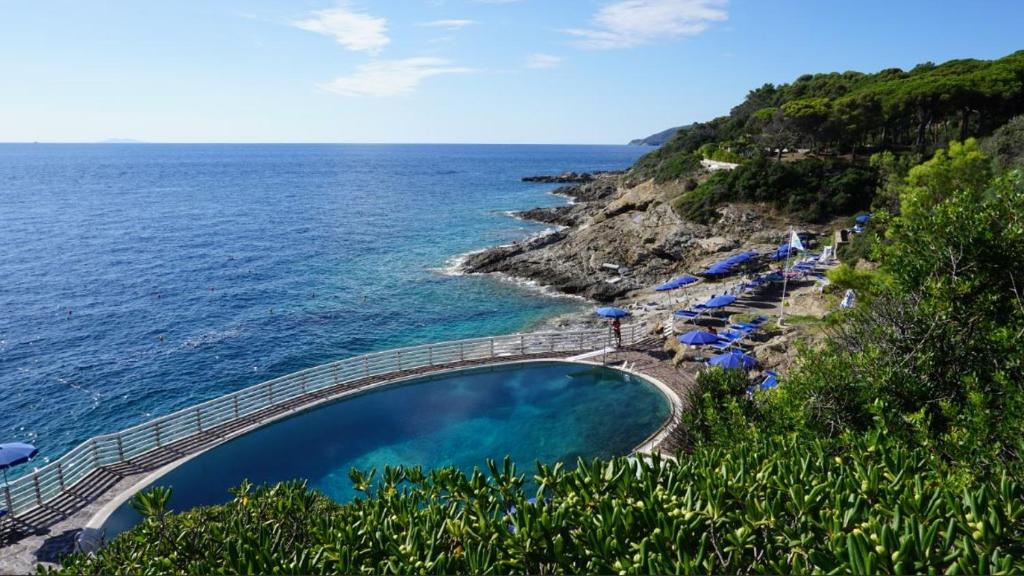 里奥马里纳Trilocale a Capo d'Arco Vista Mare的毗邻大海的带遮阳伞的游泳池