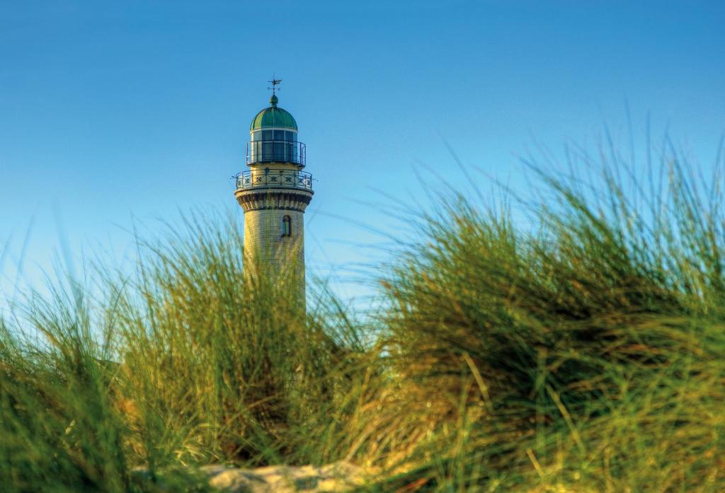 瓦尔内明德瓦尔内明德度假公寓的一座灯塔,位于海滩上,靠近草地