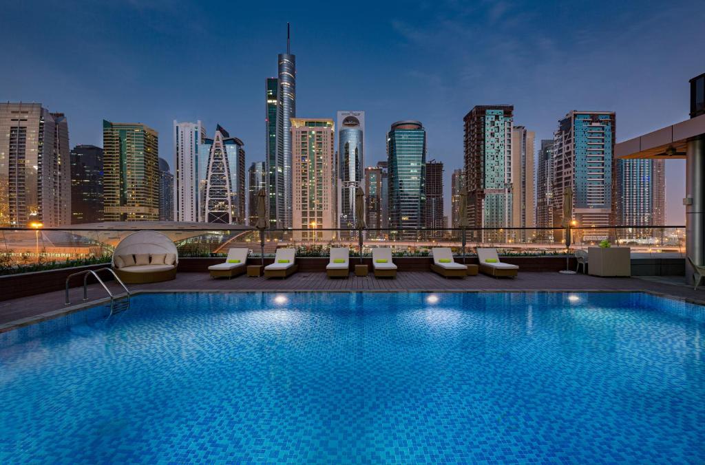 迪拜Millennium Place Dubai Marina的一座酒店游泳池,其背景是城市天际线