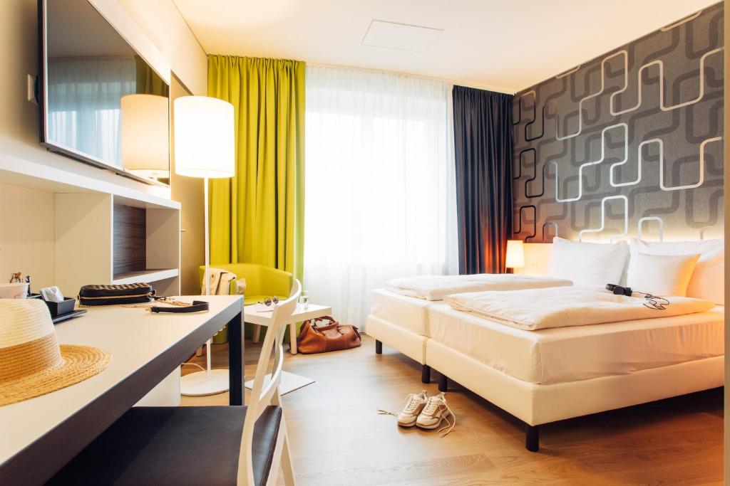 瓦利塞伦harry's home Zürich-Wallisellen的配有一张床和一张书桌的酒店客房