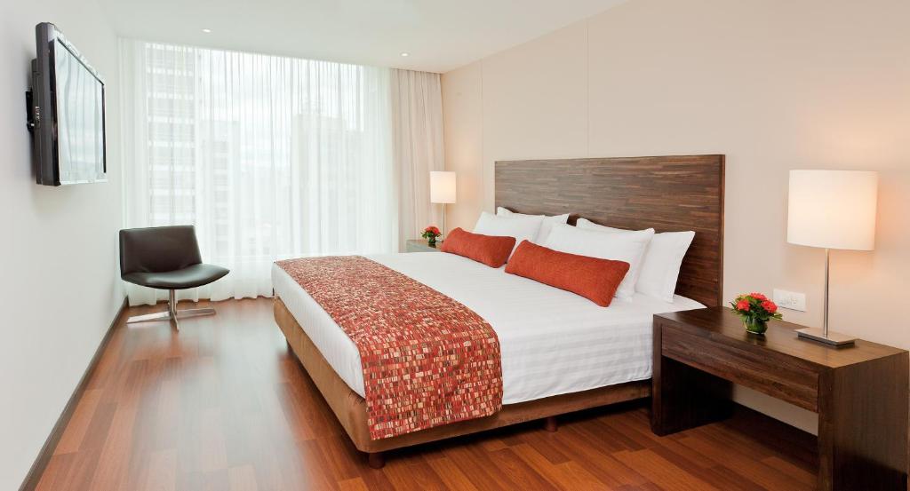 波哥大埃斯特拉100大道酒店的一间卧室配有一张床、一张书桌和一台电视
