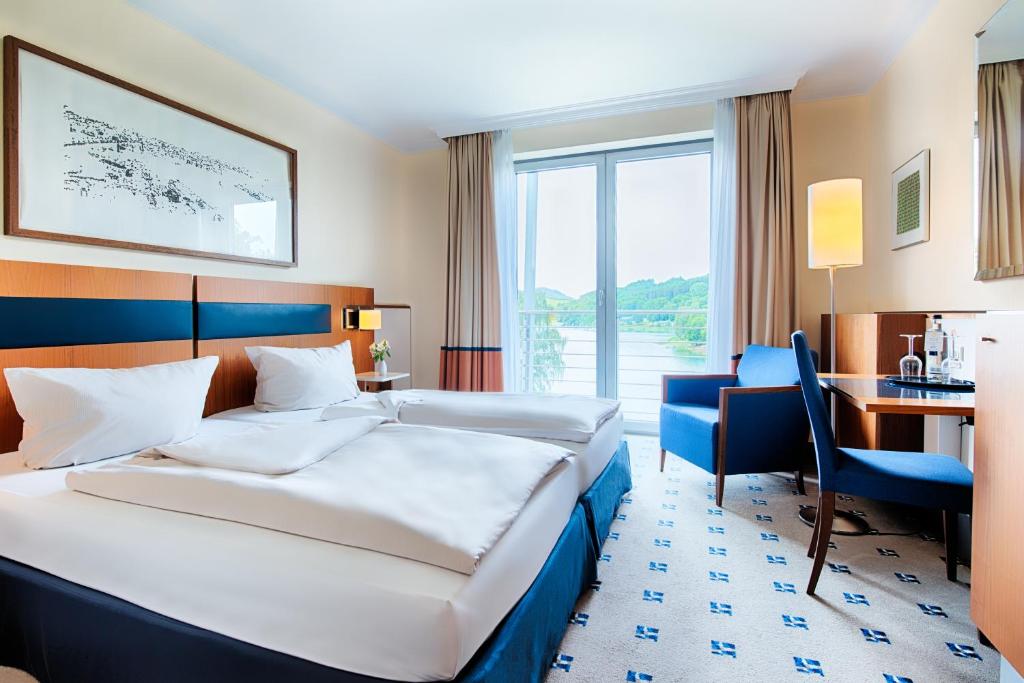 梅舍德Welcome Hotel Meschede Hennesee的酒店客房设有两张床、一张书桌和一个窗户。