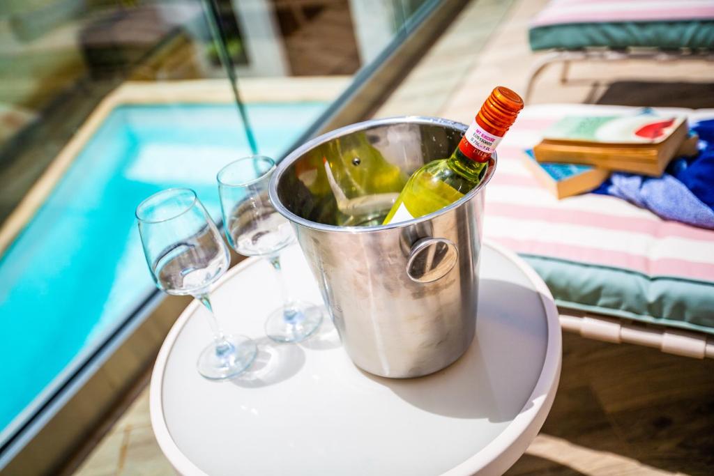 SiġġiewiPjazza Suites Boutique Hotel by CX Collection的游泳池畔桌子上一桶葡萄酒和玻璃杯