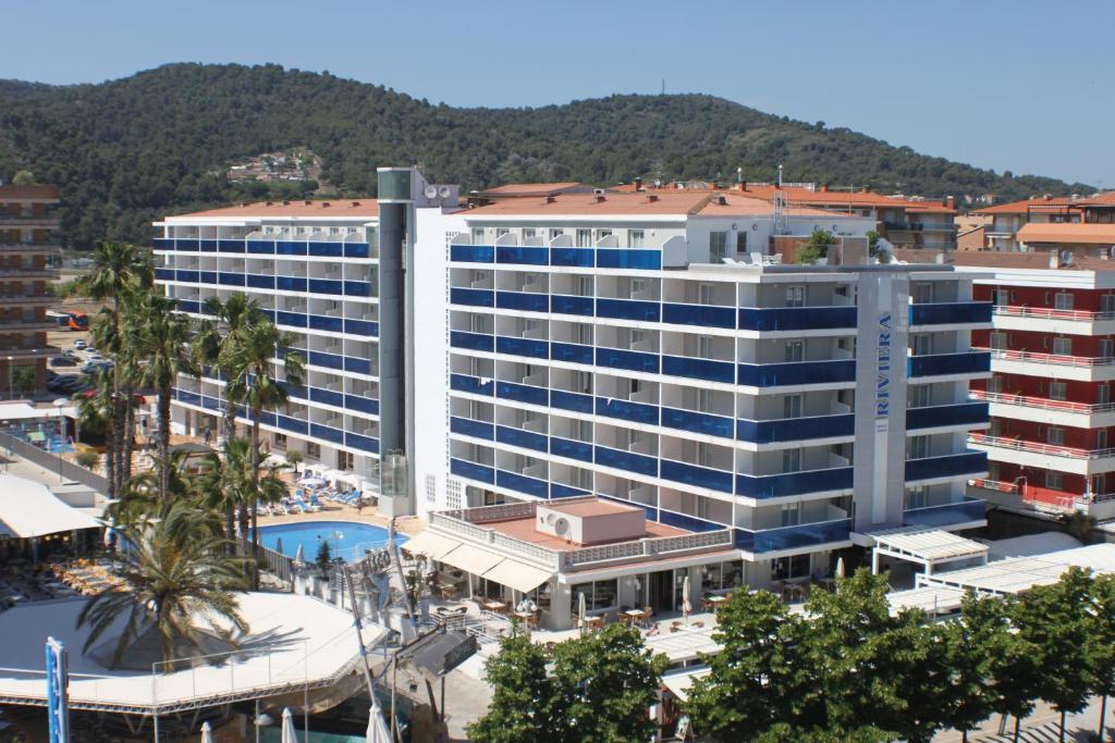 圣苏珊娜里维埃拉酒店 的一座白色的大建筑,前面设有一个游泳池