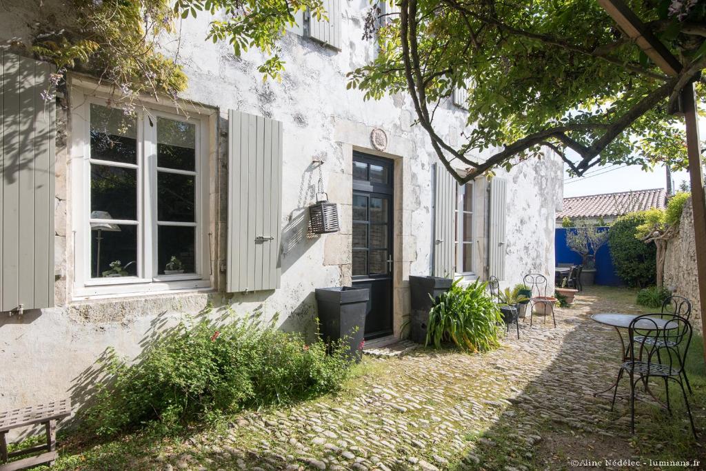 滨海拉库阿尔德Le Clos du Vieux Porche的白色的建筑,设有窗户和桌椅