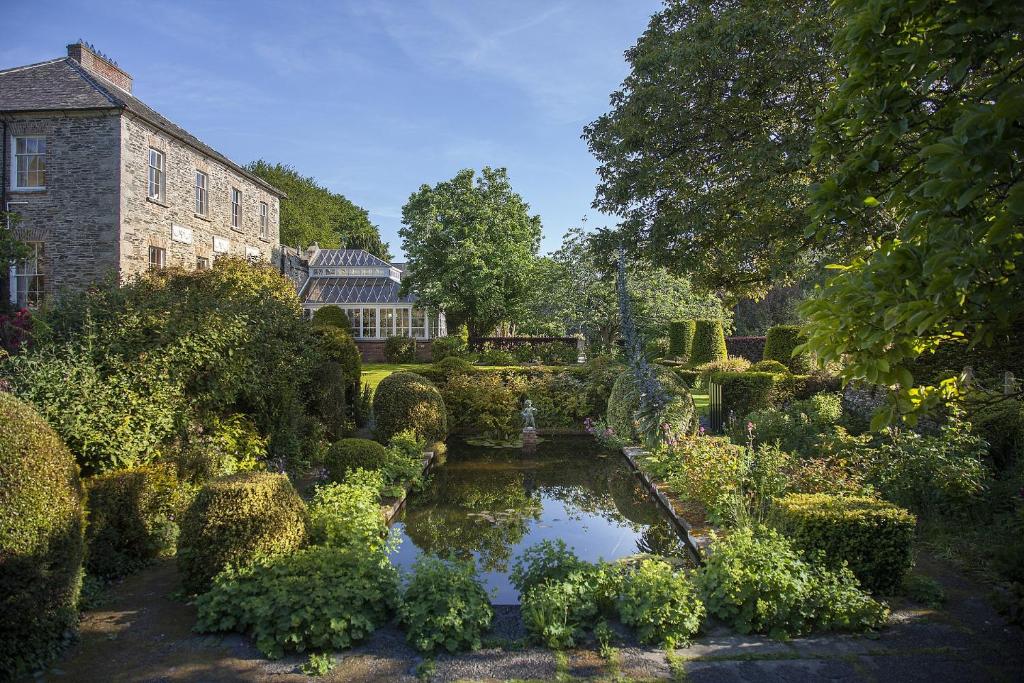 新罗斯Kilmokea Country Manor & Gardens的一座花园,在一座建筑前设有一个池塘