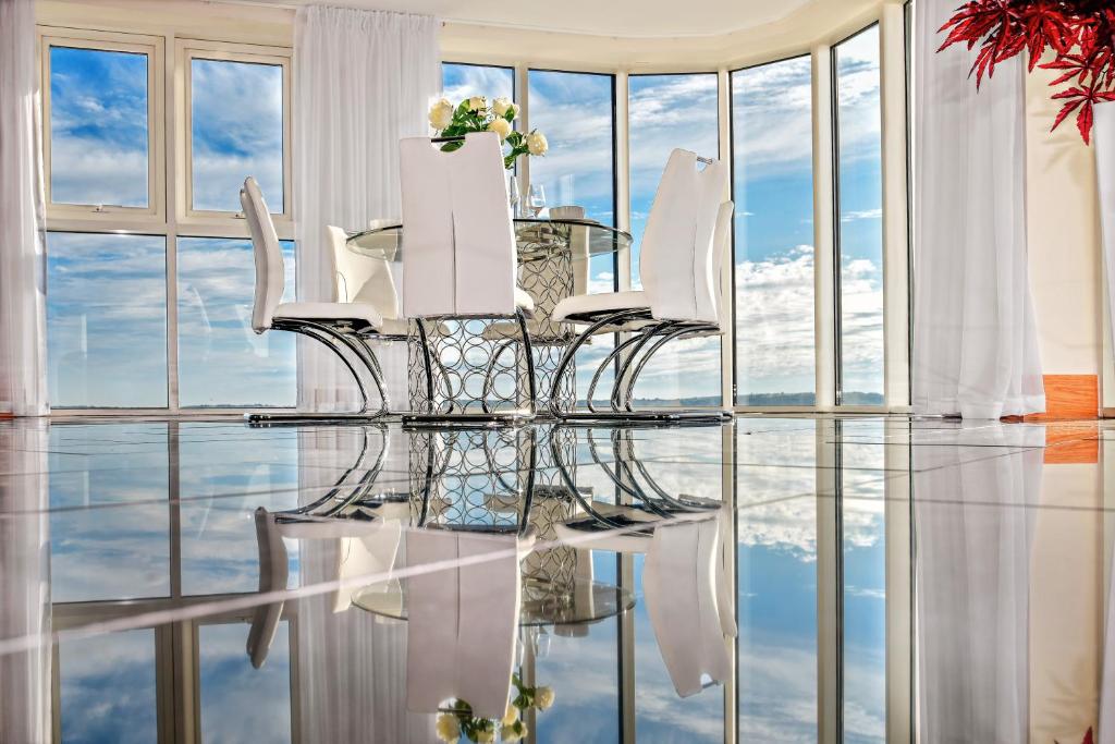斯旺西Just Stay Wales - Meridian Quay Penthouses的一间设有玻璃桌和白色椅子的用餐室