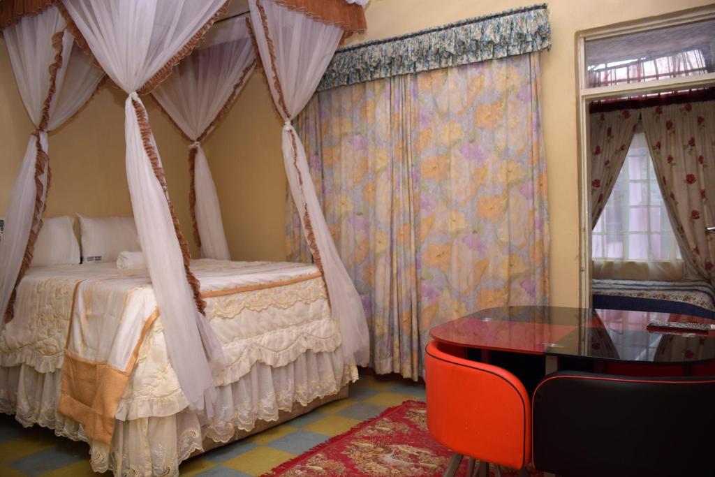 ThikaRight Venue Hotel的一间卧室配有天蓬床和玻璃桌