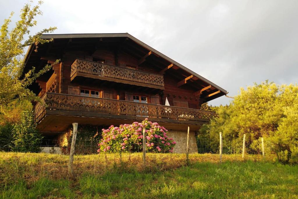 吕格兰Chalet paisible dans la nature avec belle vue sur le lac Léman的带阳台和粉红色鲜花的木屋