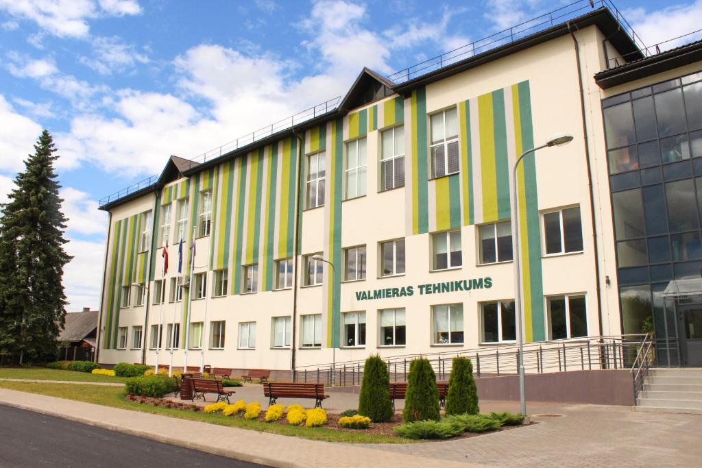 瓦尔米耶拉Valmieras tehnikuma dienesta viesnīca的一座白色的大建筑,有绿色和黄色的条纹