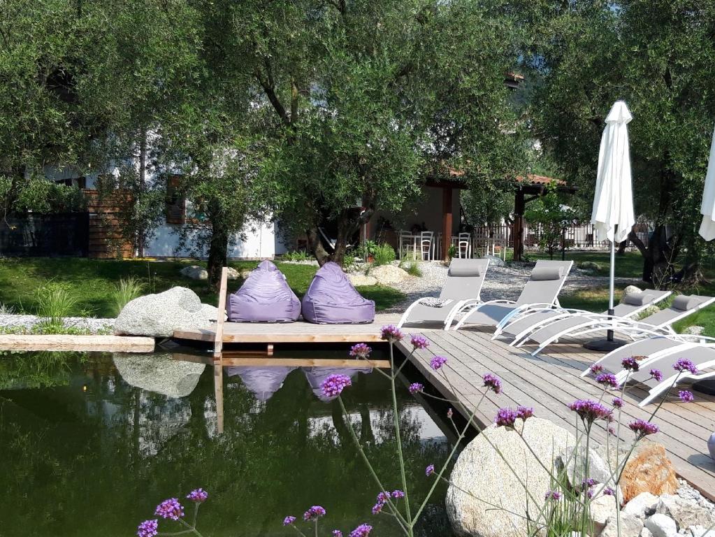 加尔达湖滨Agritur Fiore d'Ulivo的池塘旁的一组椅子和一把伞