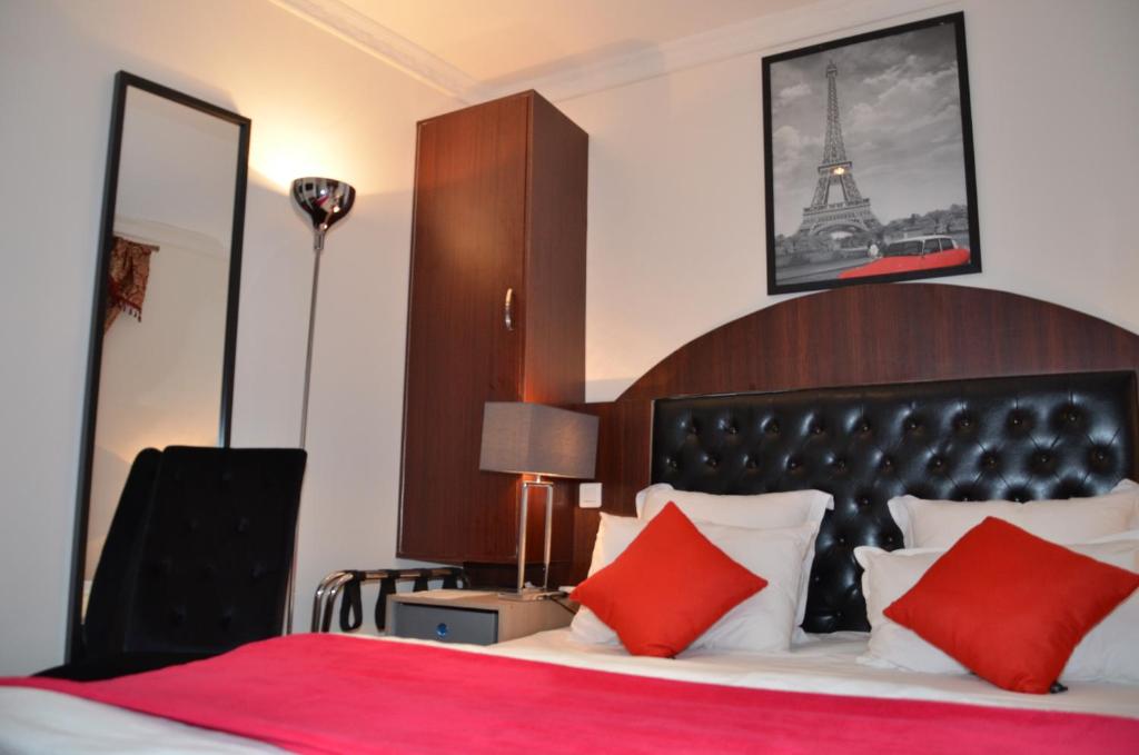 巴黎蒙马特莱吉纳酒店的一间卧室配有一张带红色枕头的床和艾菲尔铁塔