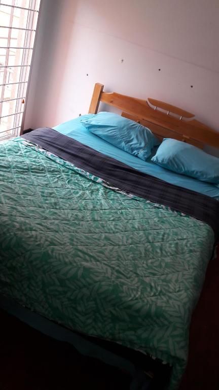 通哈Habitaciones Altos de Cooservicios的一间卧室配有一张带绿色棉被的床