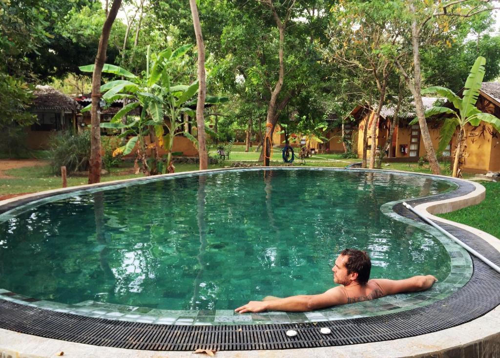 锡吉里亚Sat Nam Village Eco-Hotel的躺在游泳池里的男人