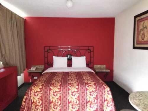 提华纳Hotel Descanso Inn的红色的卧室,配有一张红色墙壁的床