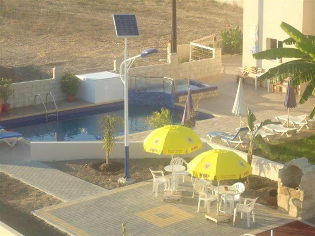 皮尔瓦利亚马力欧公寓酒店的游泳池旁的两把黄色遮阳伞和椅子