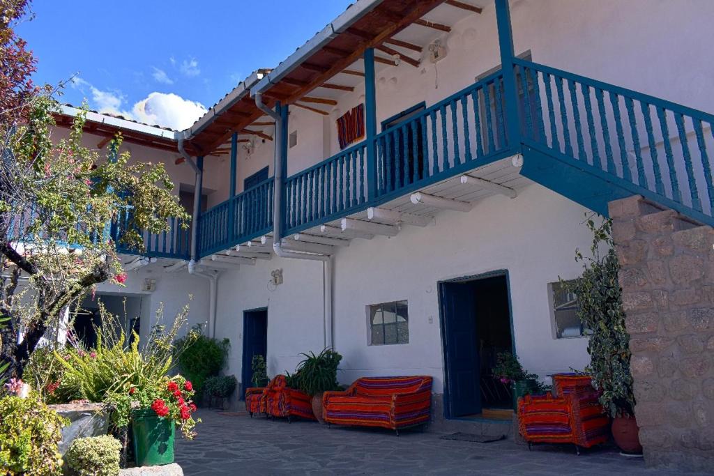 库斯科La Estacion San Pedro的白色的建筑,设有蓝色的楼梯和橙色的椅子