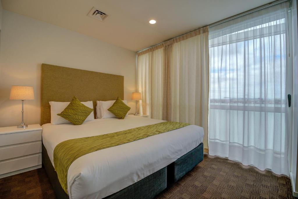 奥克兰卡德兰特酒店及套房的一间卧室设有一张大床和一个大窗户