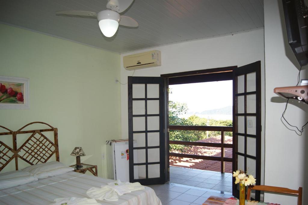 曼加拉蒂巴科斯塔克雷斯旅馆的一间卧室设有一张床,并有通往阳台的门