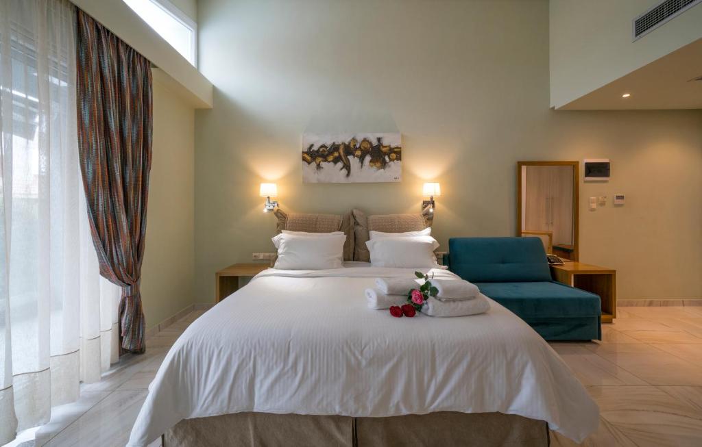 尼亚普拉莫斯Edem Luxury Apartments的卧室配有一张白色大床和一张蓝色椅子